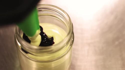 Crème ajoutée à la confiture dans un bocal en verre pour préparer un dessert traditionnel
