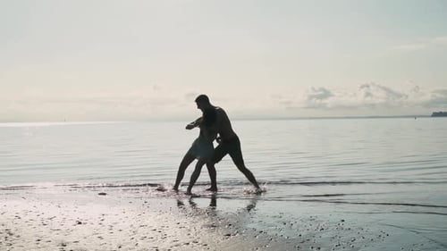 Paarkonflikt am Strand, gewalttätiger Mann attackiert Frau, Silhouettenansicht in Zeitlupe