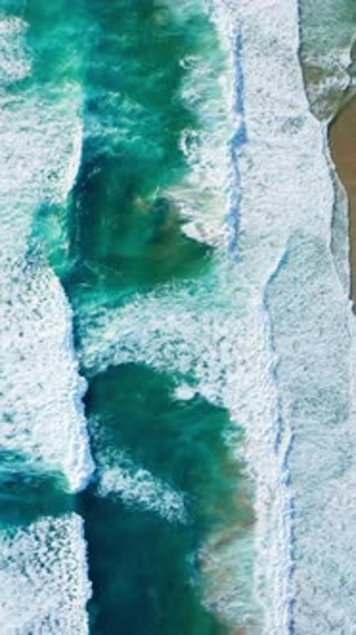 Aerial View of Beach Waves Crashing Onto Shore Creating Serene Scene Amidst Turquoise Ocean