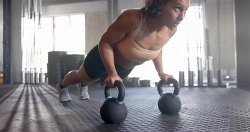 Doing push-ups using kettlebells, woman exercising in gym for fitness