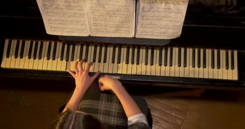 A Pianist Skillfully Playing Sheet Music From Above with Grace and Precision in a Concert Hall