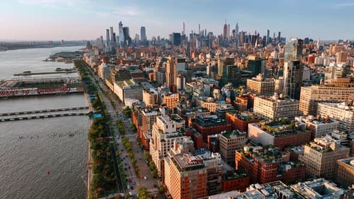 Densely built panorama of New York at sunset. Lively highway on the waterfront near the river.