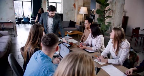 Teamwork at Trendy Coworking Office Young Coach Businessman Using Tablet to Present Data at Team