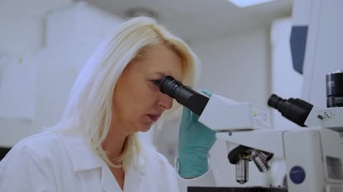 Woman Scientist Looks Through Microscope in Lab