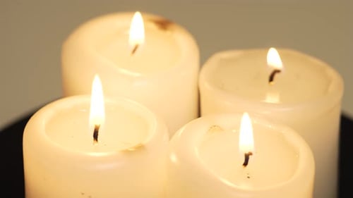 Spirituelles Ritual Vier weiße Paraffinkerzen brennen und drehen sich auf dem Tisch, Nahaufnahme