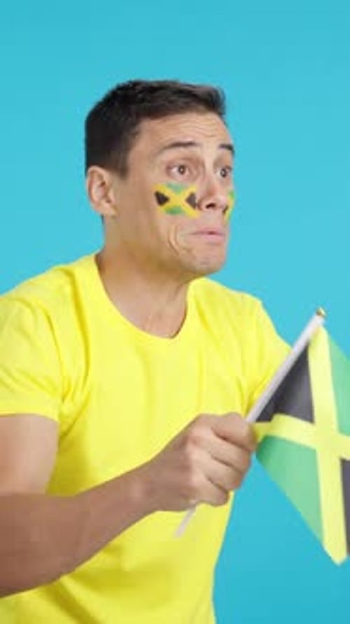 Nervous Man Cheering for Jamaica During a Match Looking Away