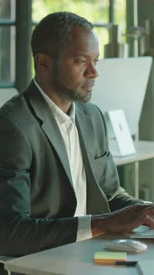 A Professional Man Diligently Working on His Laptop Within a Modern Office Environment