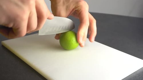Hands Cutting a Fresh Lime with Sharp Knife