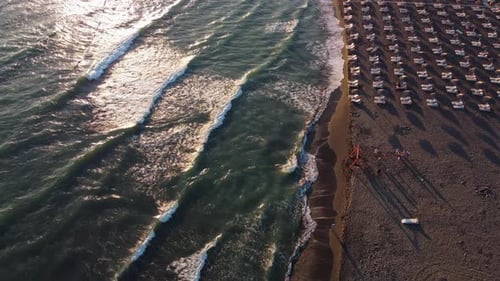 Aerial Drone View of Sand Beach with Rows of Straw Umbrellas and Sun Loungers By Sea with Strong