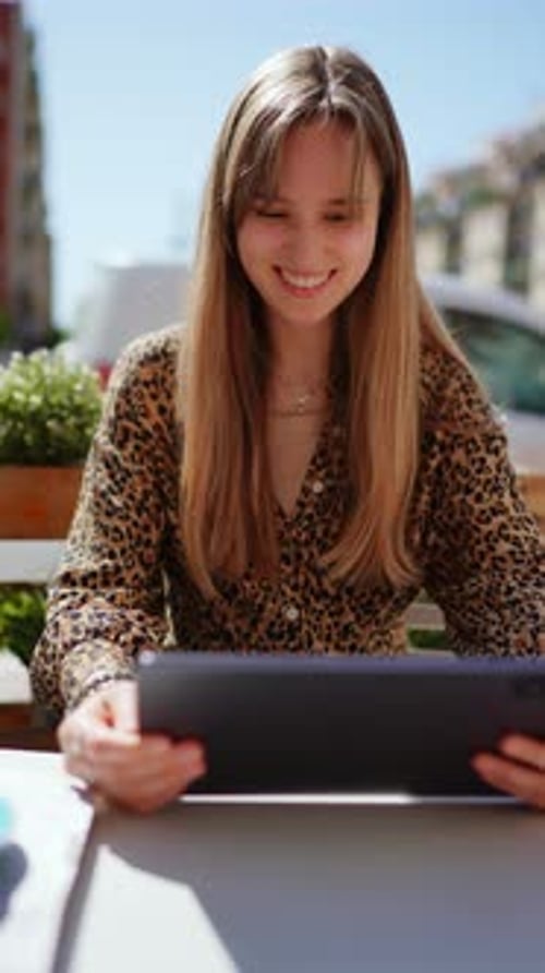 Female Professional Networking Remotely Smiling While Working on Tablet at Sunlit Outdoor Cafe City