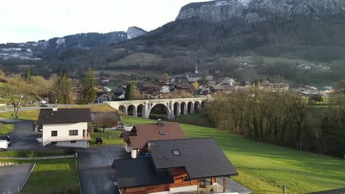Beautiful white brick bridge over river with small French town and mountains in the background and g