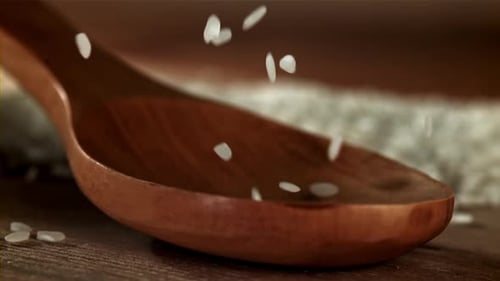 Reis fällt in einen Holzlöffel, gefilmt mit einer Hochgeschwindigkeitskamera mit 1000 Bildern pro Sekunde