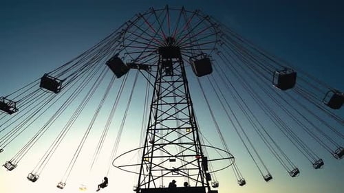 Spinning Carousel Silhouette at Sunset in Amusement Park