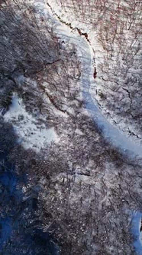 Vertical Winding Road Through Snowy Forest Aerial View