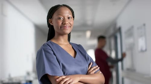 Portrait of happy african american female doctor wearing scrubs in hospital, slow motion