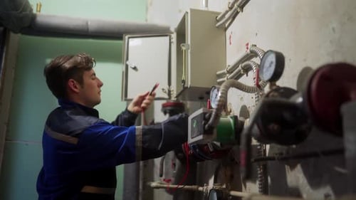 Electrician Inspecting Control Panel with Multimeter in a District Heating Substation Goes Away and
