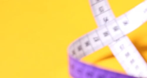 Purple Measuring Tape Rolls over Yellow Background