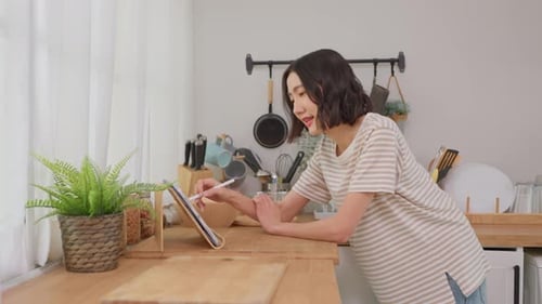 Woman Uses Stylus on Tablet in Bright Kitchen