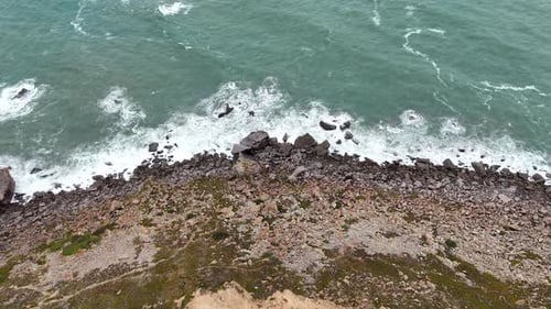 This Aerial View Showcases the Rugged Beauty of a Rocky Shoreline with Turquoise Waves