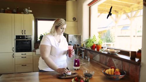 Woman Making and Drinking Smoothie in Kitchen