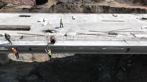 Aerial view of cranes and bridge foundation pillars on construction site of new highway road project