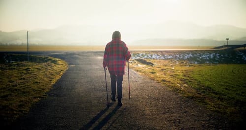 Senior Woman Walks With Walking Sticks in Countryside
