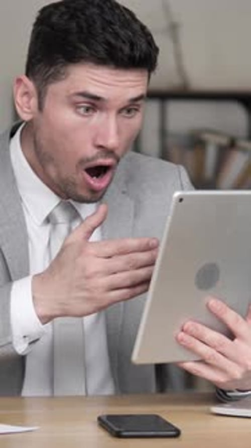 Man in Suit Using Tablet Reacts with Shock