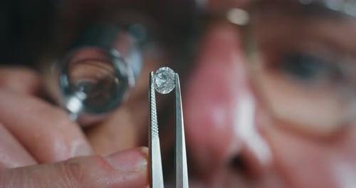 Slow motion macro close up of experienced goldsmith controlling a quality of diamond stone, select