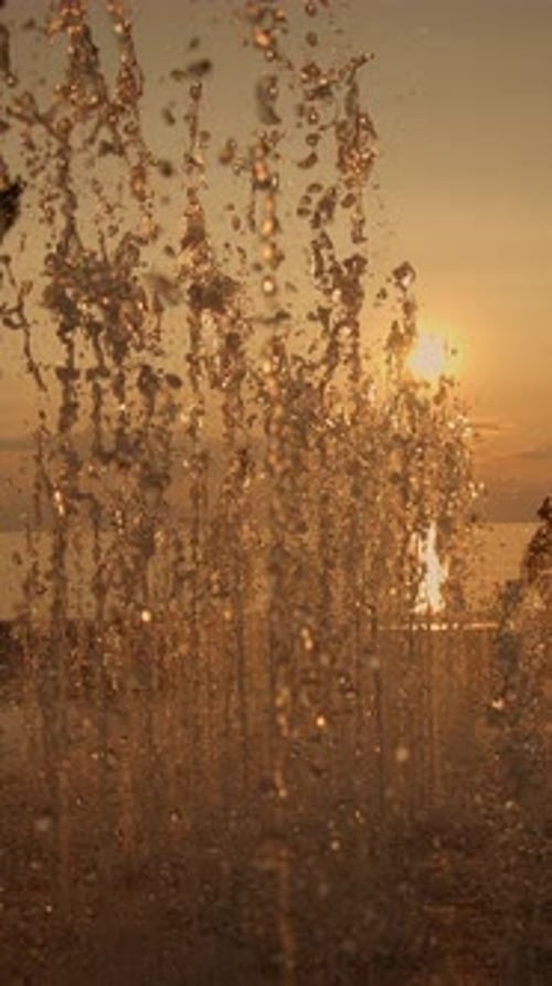 A Stunning Golden Sunset with a Beautiful and Refreshing Water Spray Captivating the Viewers Eye