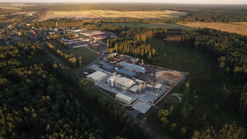 Aerial View of the Territory of Factories with Tanks and Storage Facilities Near the Village Among