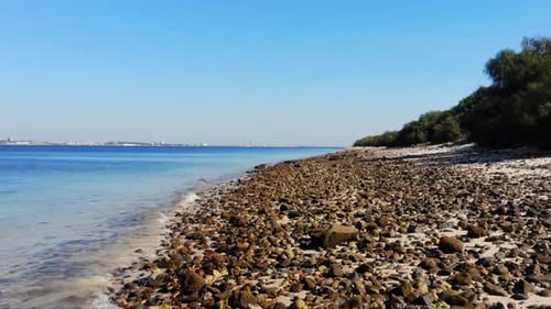 Drone flying low over the pebbles on the beach.
