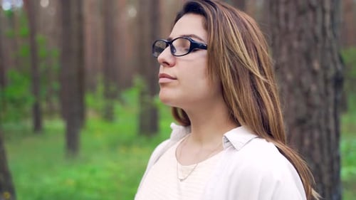 Close up portrait of a pretty young woman breathes fresh air into her full chest in the middle