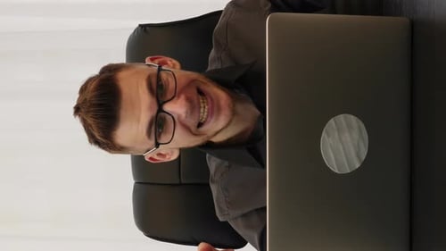 Smiling Young Adult Working on Laptop in Office