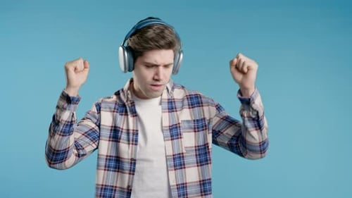 Brunette Positive Man Listening Music Dancing with Headphones Blue Studio