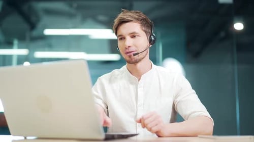 customer service support agent sits in modern office communicates online with a headset. Man special
