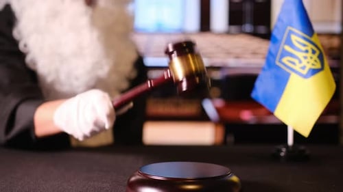 Closeup of a Judge Hand with a Gavel Beside the Ukrainian Flag in a Courtroom Setting