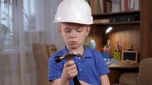 Boy Inspects a Hammer Wearing a Hard Hat