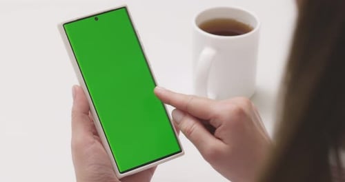 Woman with Green Screen Smartphone Scrolling Through Social Media or Online Shop