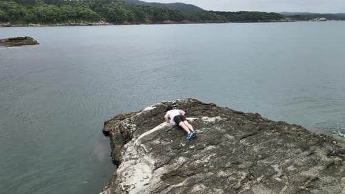 Man Does Pushups on Rocky Seashore
