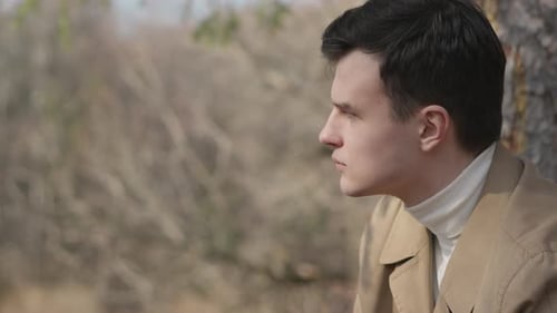 The Young Man Sits Alone in Nature in the Park with Conceived Look