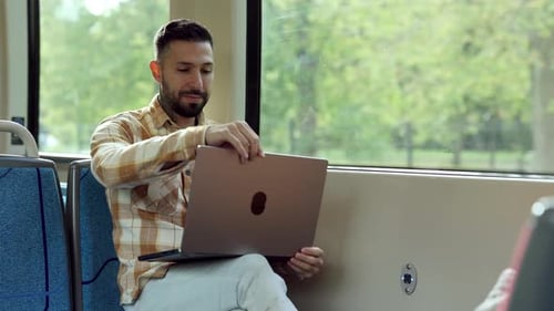 Konzentrierter Mann arbeitet während der Bahnfahrt am Laptop