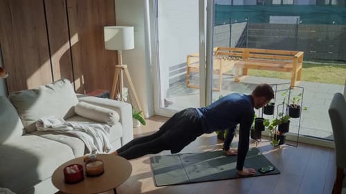 Man doing push ups on exercise mat at home in sunny living room