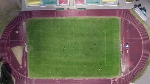 Aerial View of the Game of Football Teams in the City Stadium with Running Tracks and Colorful