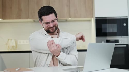 Stressed Distant Worker Experiencing Bones Ache and Bending Hand in Kitchen Area