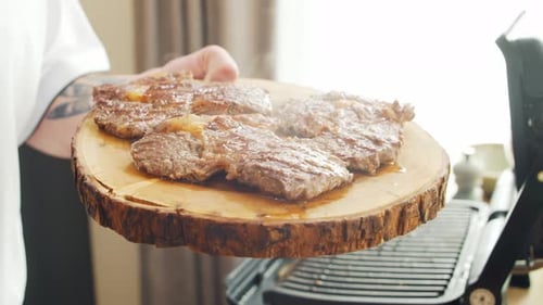 Chef Holds Steaming Steak on Wooden Board