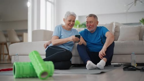Senior Couple Using Phone After Exercise at Home