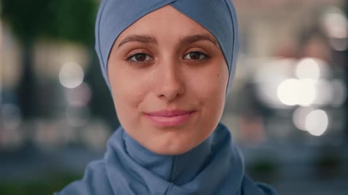 Porträt einer glücklich lächelnden arabischen Frau mit blauem Hijab, die lächelt und in die Kamera schaut