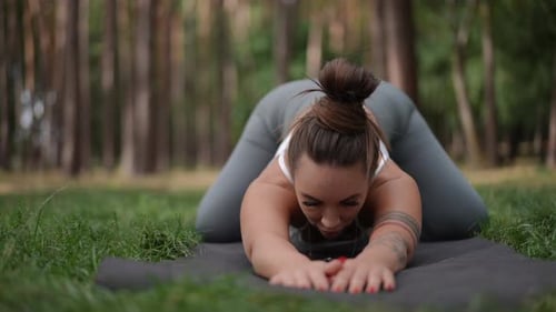 Woman Doing Yoga in Forest Stretching Body
