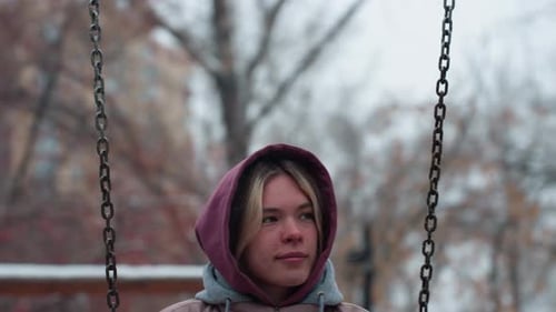 CloseUp of Young Person Holding Swing Chain in Winter Playground