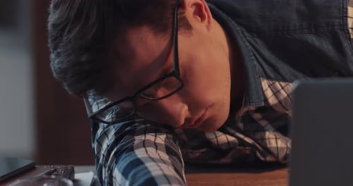 A Visibly Exhausted Student Feels Overwhelmed By an Immense Amount of Work at Their Desk